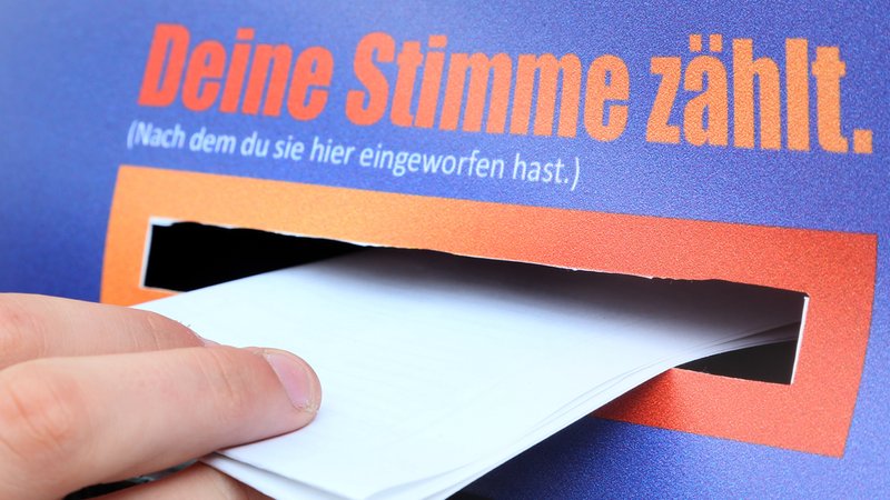 Eine Kinderhand wirft einen gefalteten Stimmzettel ein. | Bild: picture alliance / dpa | Stephanie Pilick Eine Kinderhand wirft einen gefalteten Stimmzettel ein.