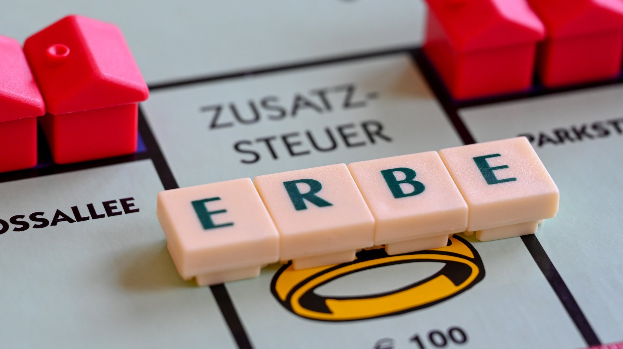 Beim Erben wird Erbschaftssteuer fällig. Scrabble-Steine mit dem Wort "Erbe" liegen auf einem Monopoly-Feld.