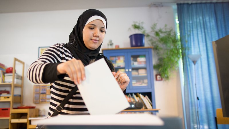Eine junge Frau mit Kopftuch gibt in einem Wahllokal ihre Stimme ab. | Bild: picture alliance / dpa | Maja Hitij Eine junge Frau mit Kopftuch gibt in einem Wahllokal ihre Stimme ab.