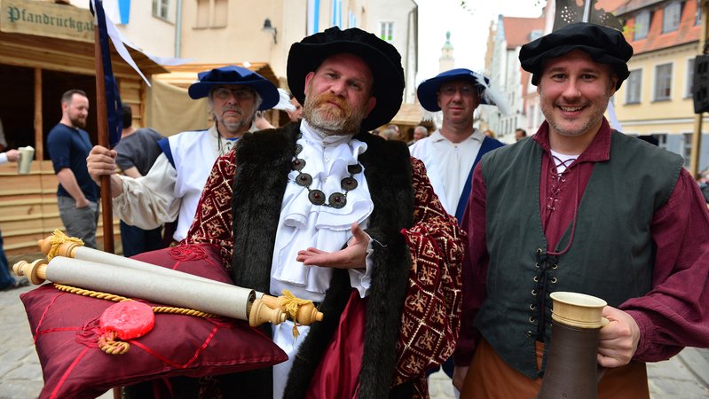 Zwei Männer posieren in mittelalterlichen Outfits mit Schriftrolle und Bierkrug an einem vergangenen Fest des Reinen Bieres.