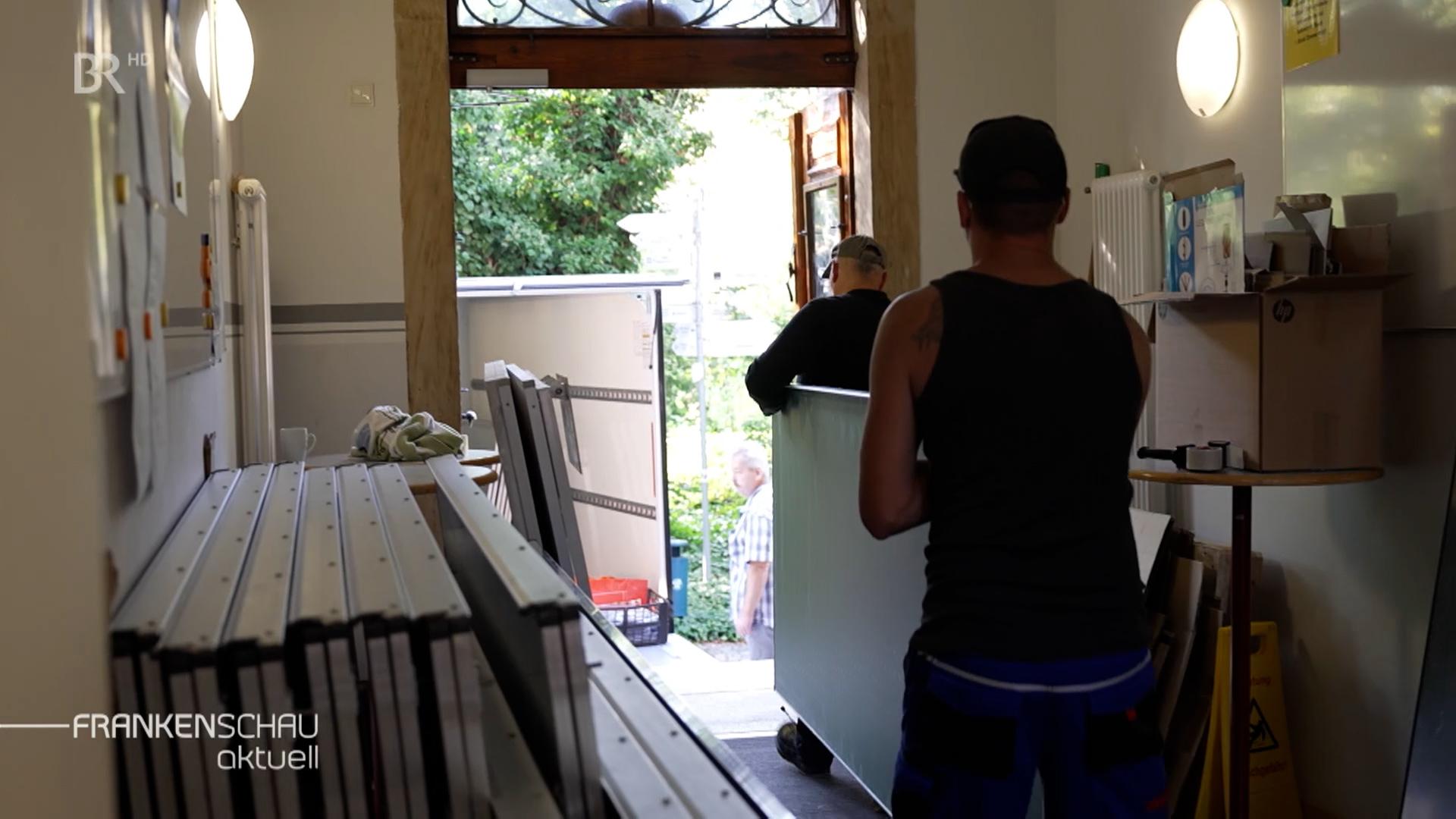 Zwei Männer tragen eine Tafel.