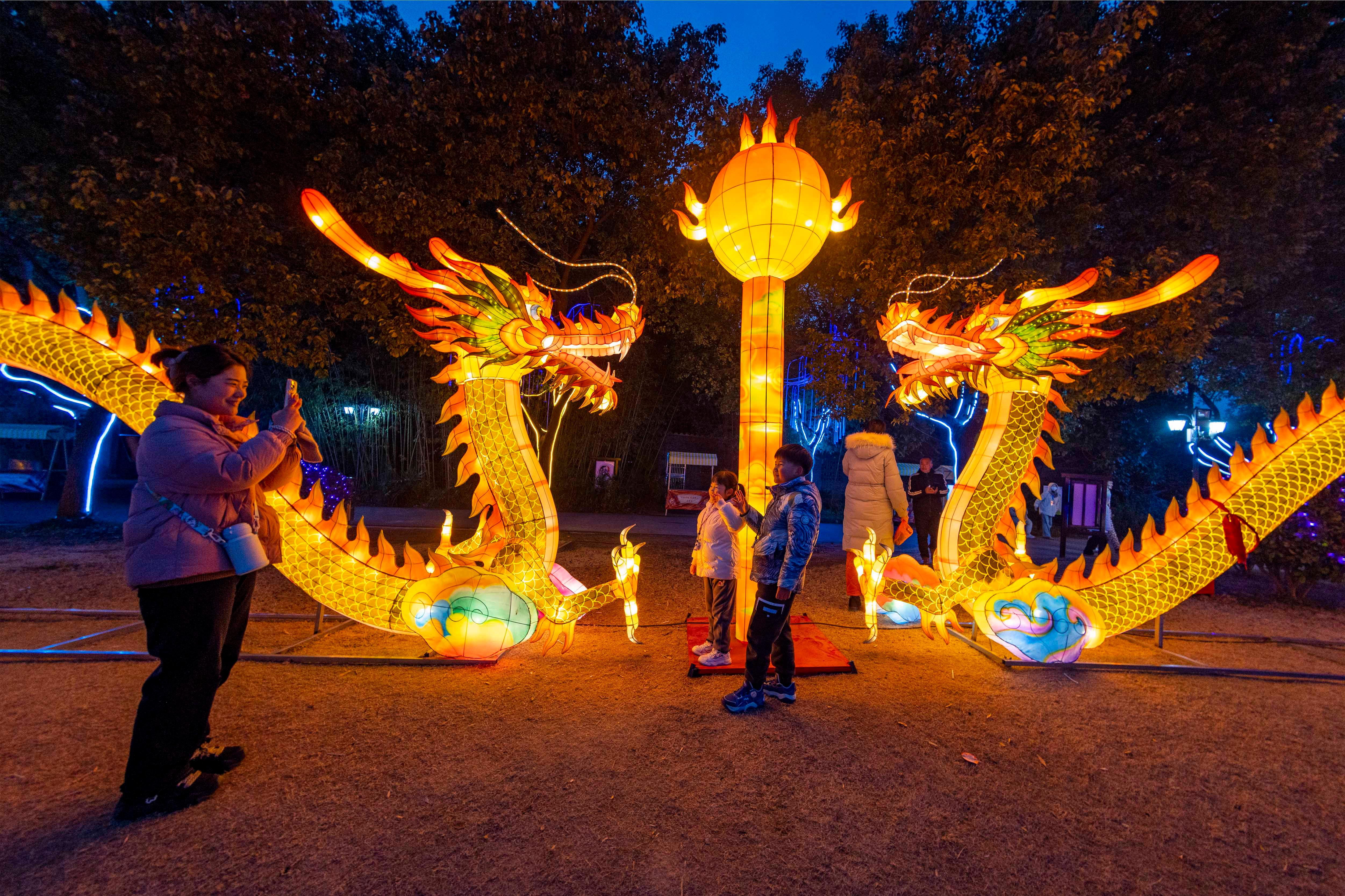 Passanten fotografieren sich vor illuminierten Drachen-Figuren