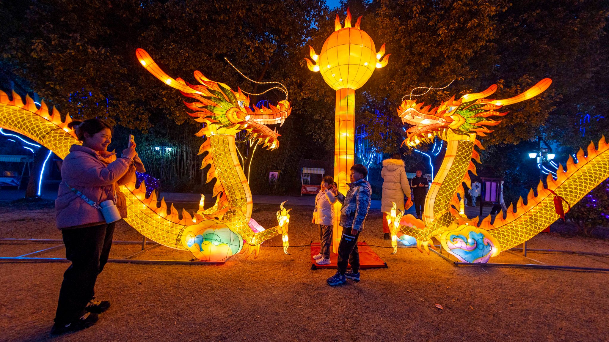 Passanten fotografieren sich vor illuminierten Drachen-Figuren