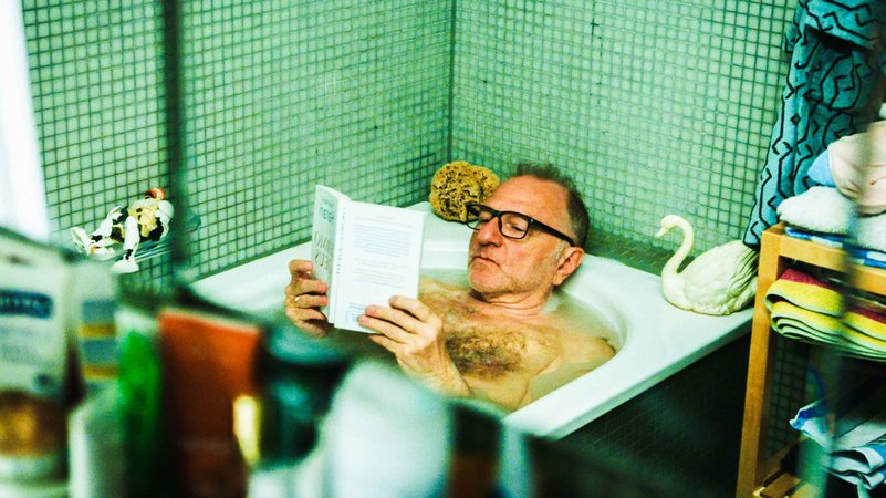 Ein Mann liegt mit einem Buch in einer Badewanne (Filmszene aus "Wir Eltern").