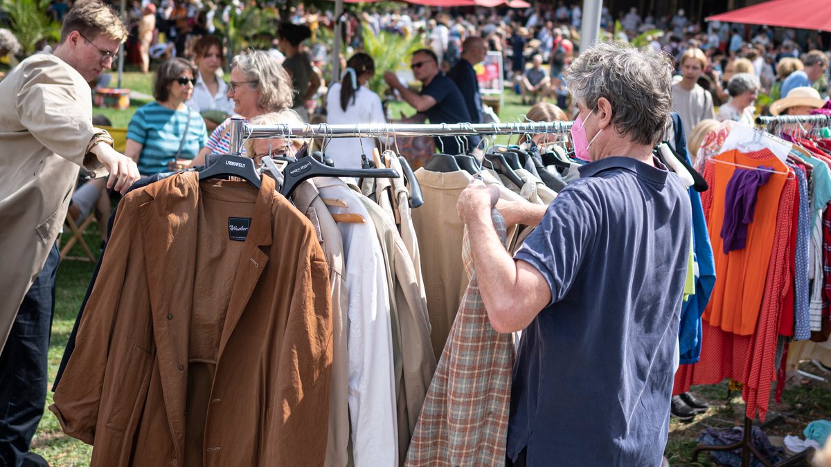 Kunden beim Inspizieren der Kleidung auf einem Flohmarkt (Symbolbild)