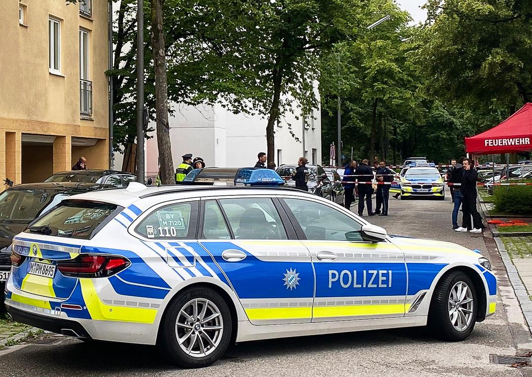 Einsatzkräfte der Polizei stehen vor einem Mehrfamilienhaus im Stadtteil Milbertshofen. Der Ort, an dem ein Mann niedergeschlossen wurde, ist abgesperrt.