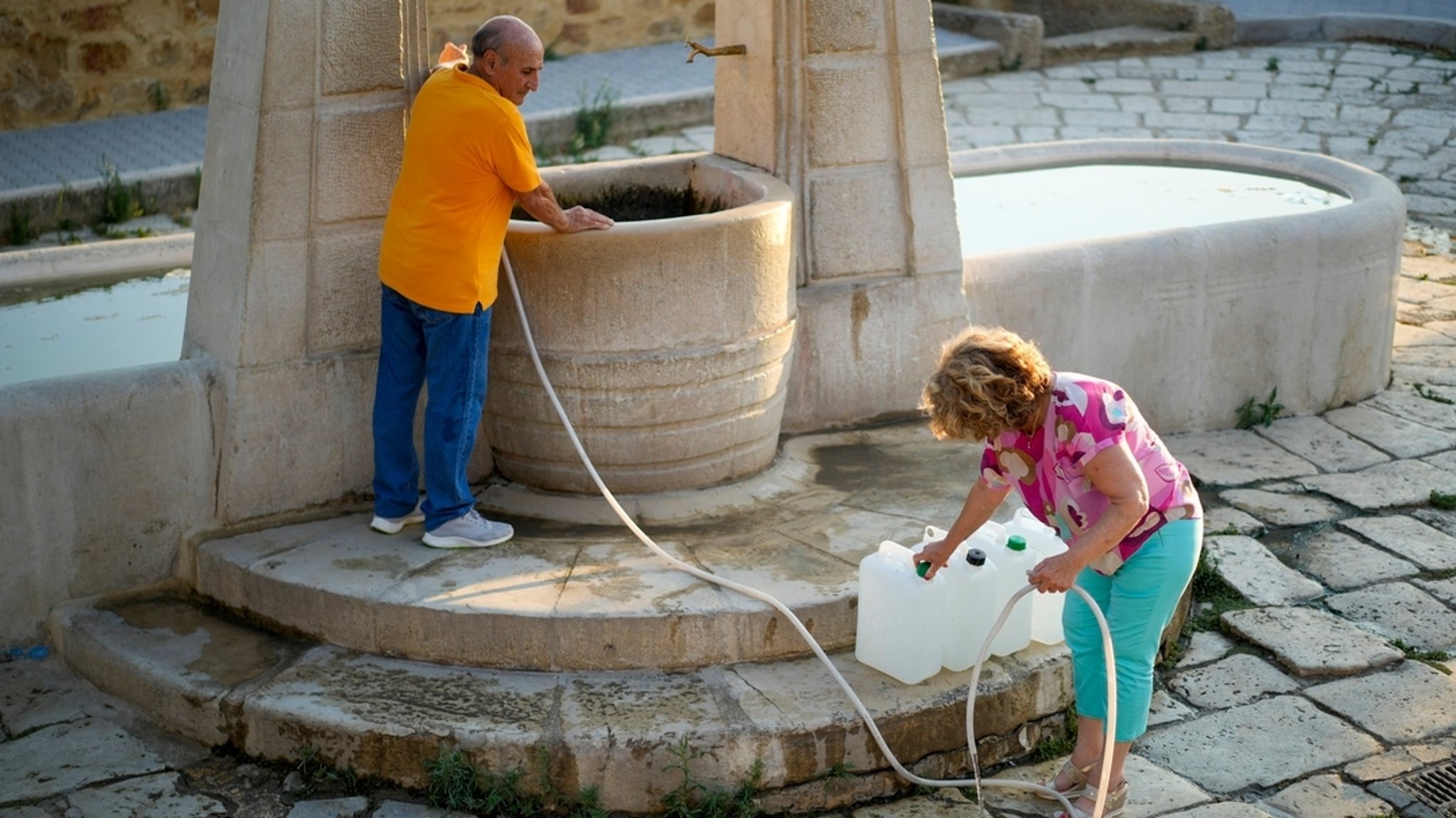 Einwohner füllen Kanister mit Wasser für den täglichen Gebrauch an Agrigentos einzigem öffentlichen Brunnen, nachdem sie Schwierigkeiten hatten, Wasser von den Tankwagen zu bekommen. (Archivbild vom 17.7.24)