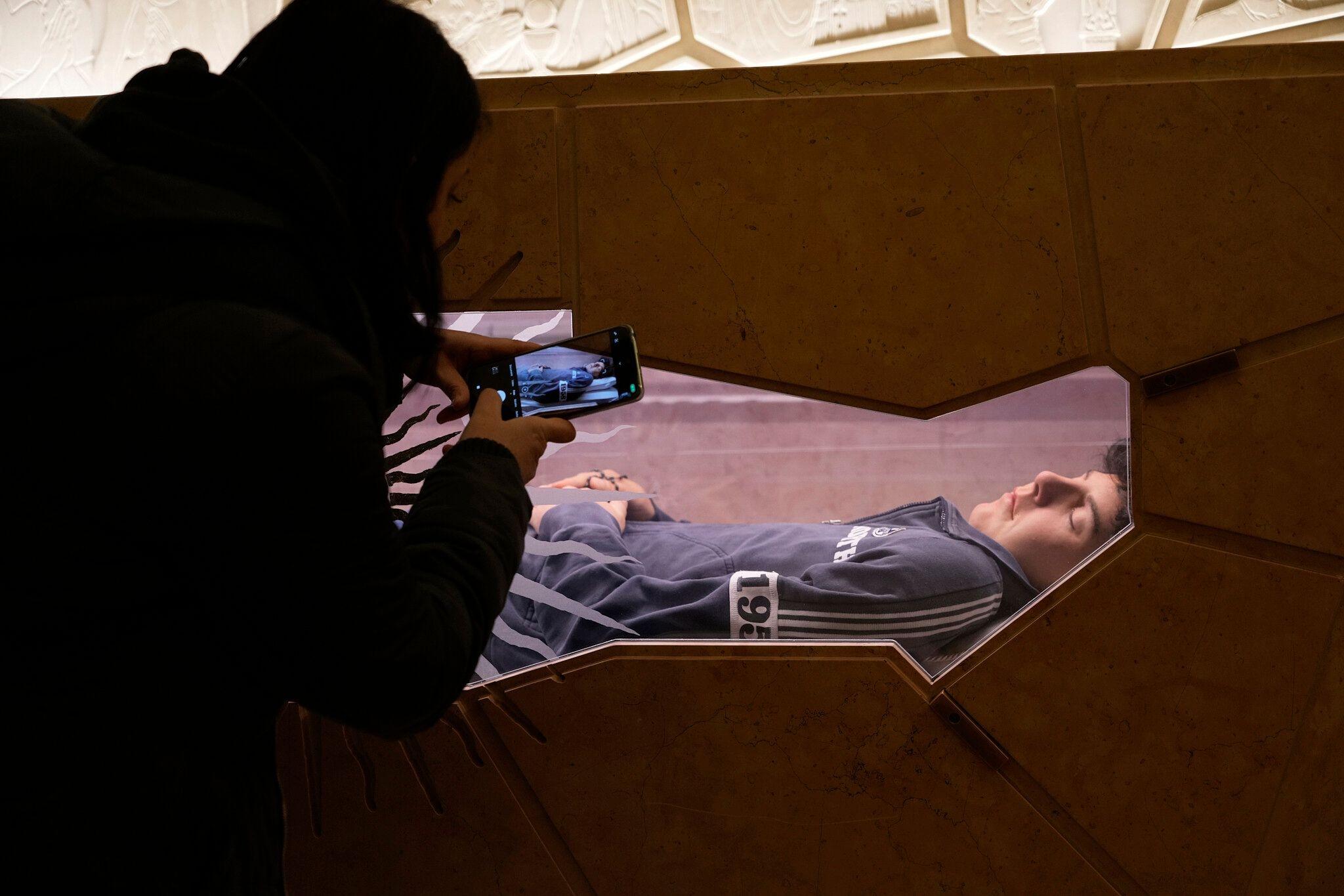 Ein Jugendlicher macht mit seinem Smartphone ein Foto am Grab des 15-jährigen Carlo Acutis.