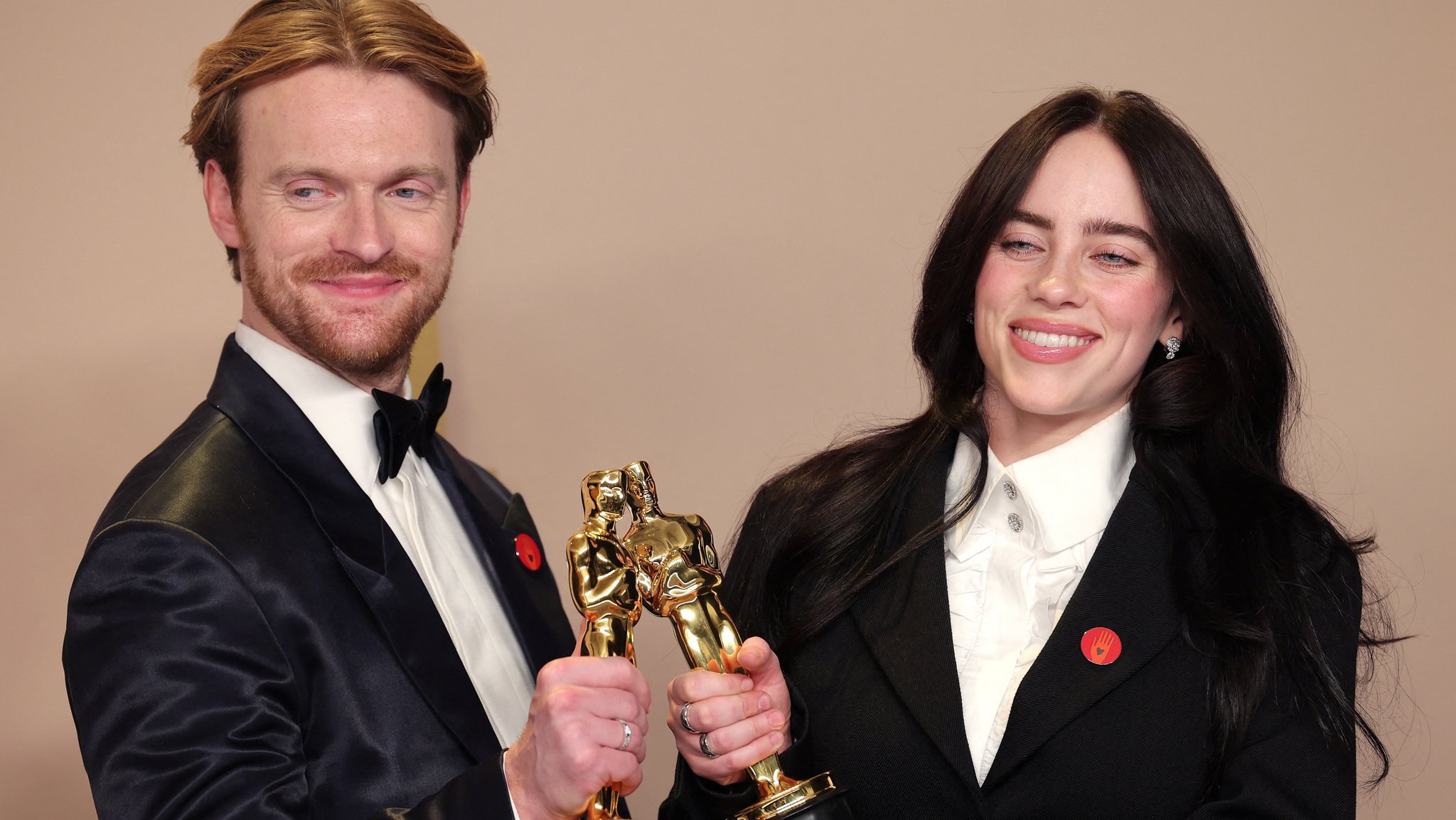 Oscarpreisträger: Sängerin Billie Eilish und ihr Bruder Finneas O'Connell tragen an ihren Anzügen einen roten Button, der für den Aufruf zu einem sofortigen Waffenstillstand im Gazastreifen steht.