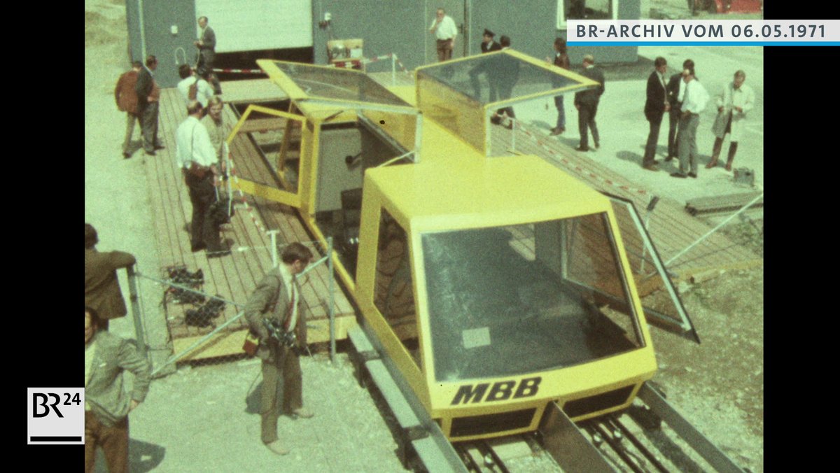 Menschen beim Betrachten der gelben Magnetschwebebahn von der Firma Messerschmitt-Bölkow-Blohm