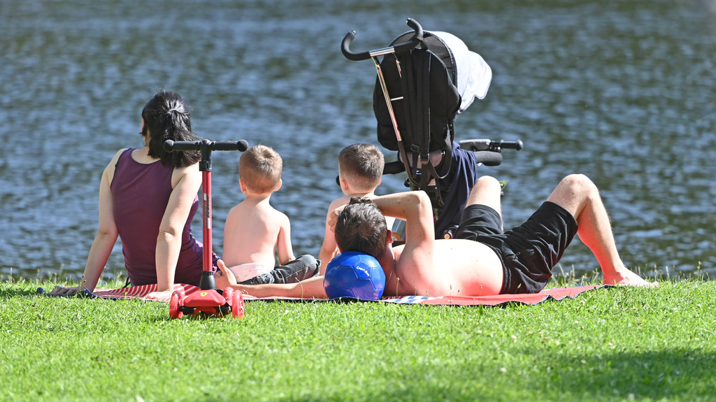 Eltern mit ihren zwei kleinen Kindern erholen sich am Olympiasee im Olympiapark in München (Symbolbild).