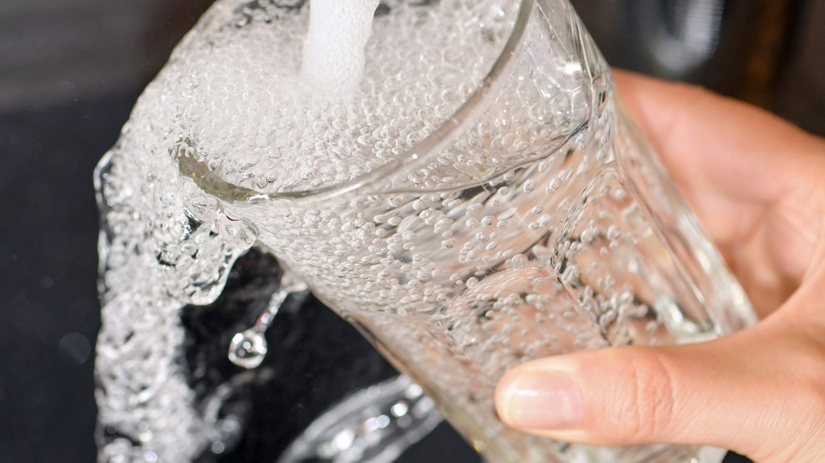 Am Wasserhahn in einer Küche wird ein Trinkglas mit Leitungswasser gefüllt (Symbolbild)