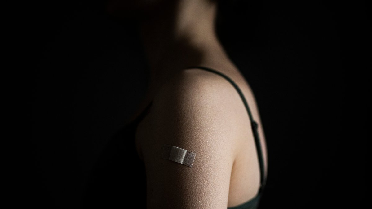 Ein Pflaster klebt auf dem linken Oberarm einer gegen Corona geimpften Frau