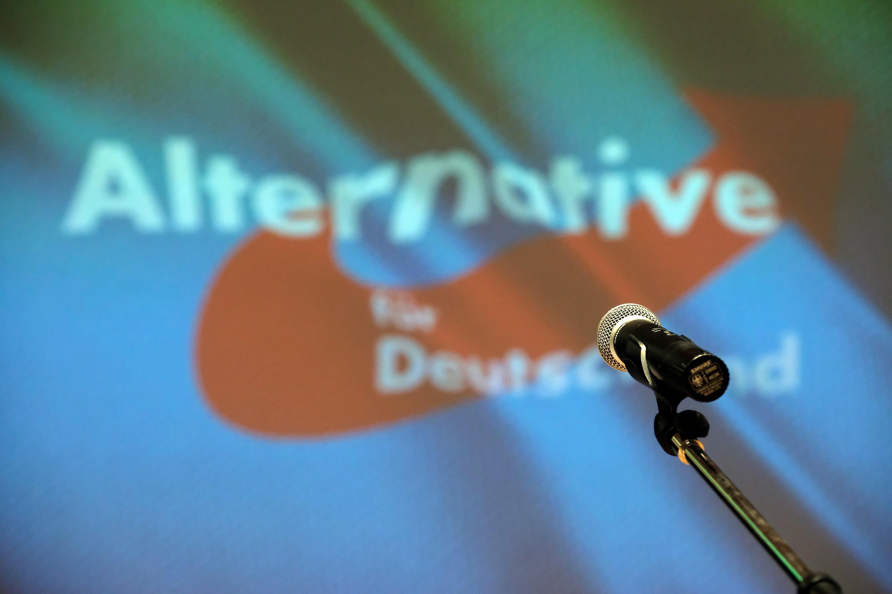 Ein Mikrofon steht beim Landesparteitag der der sächsischen AfD auf der Bühne vor dme Partei-Logo.
