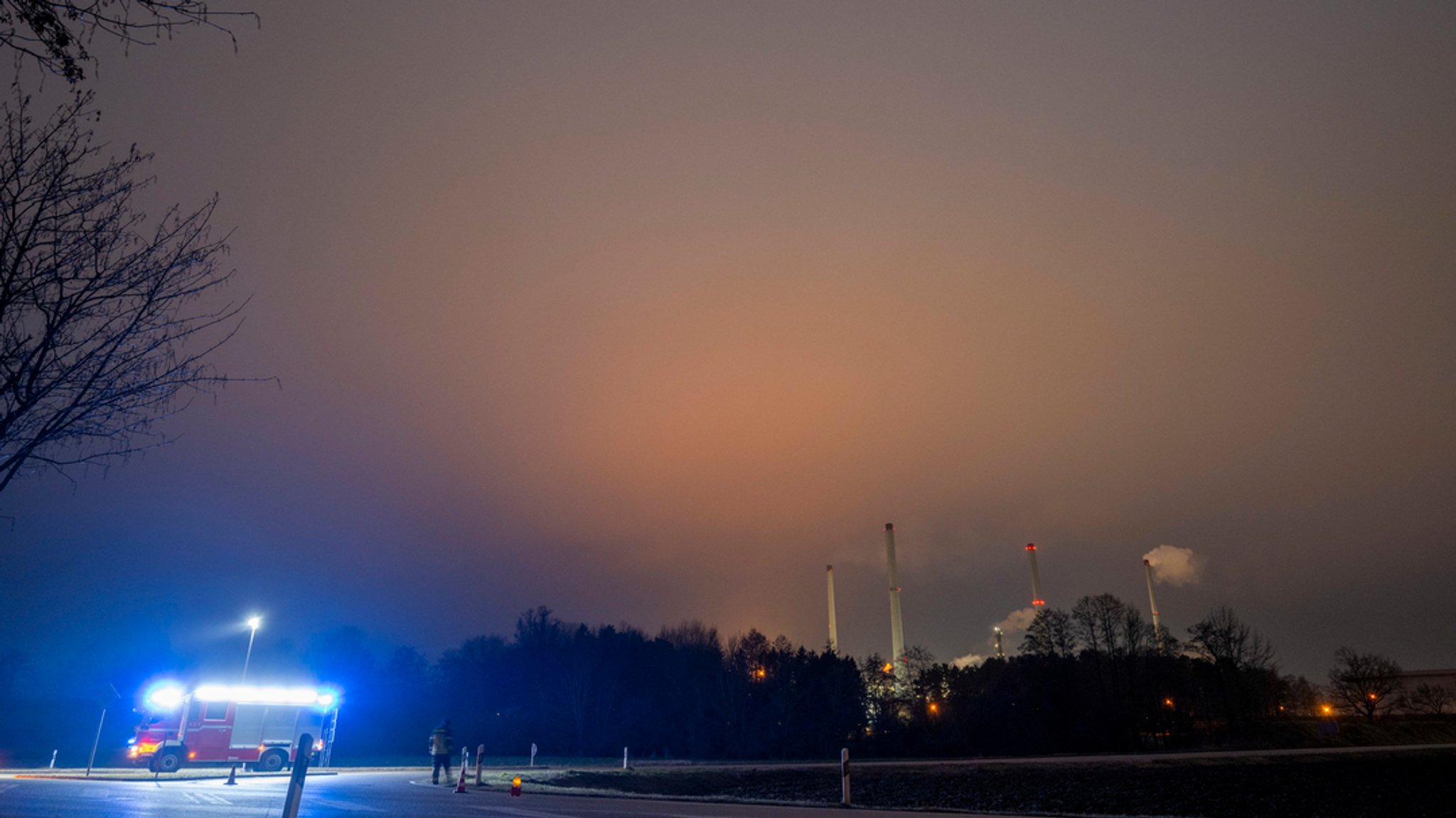 Nachthimmel, orange gefärbt, im Vordergrund ein Einsatzwagen der Feuerwehr