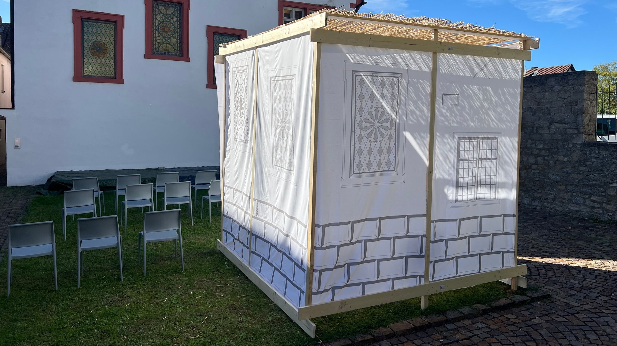 Im Synagogenhof steht eine Sukka. Ihre Wände sind aus weißem Stoff. Das Dach ist aus Bambus. | Bild: BR / Vincent Poschenrieder Im Synagogenhof steht eine Sukka. Ihre Wände sind aus weißem Stoff. Das Dach ist aus Bambus.