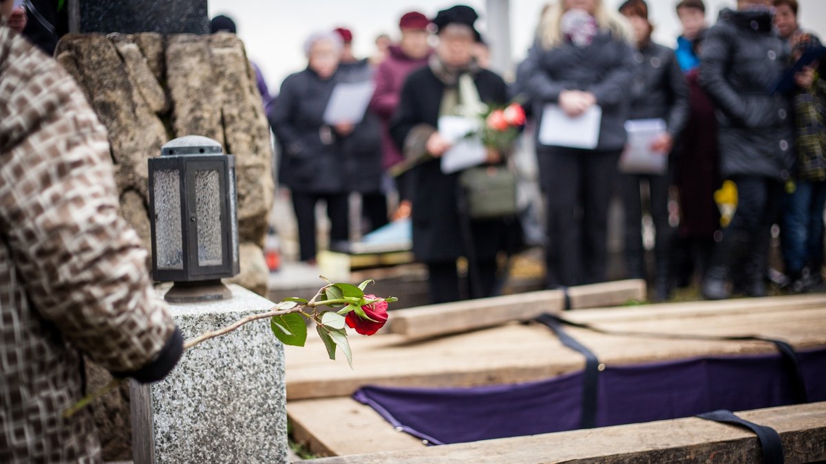 Symbolbild einer Beerdigung mit Menschen am offenen Grab.