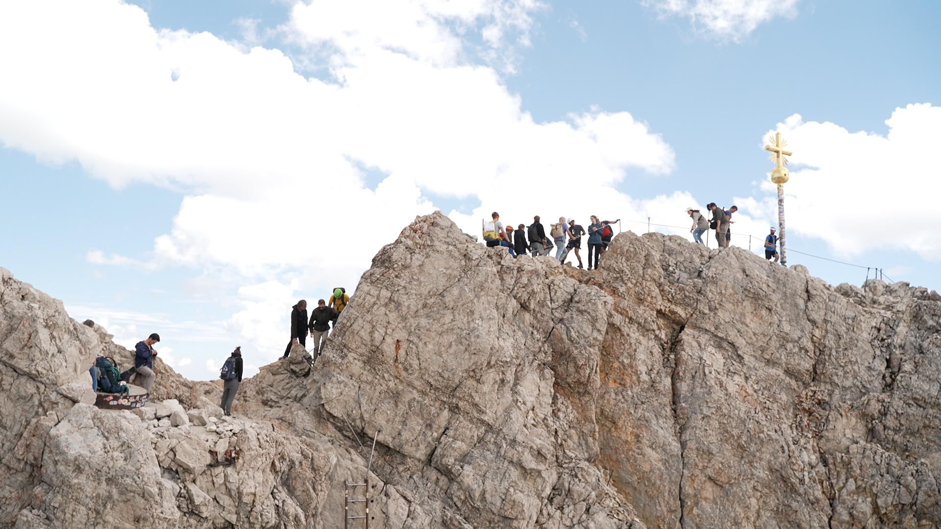 Viele Menschen drängen sich auf dem Klettersteig zum echten Gipfelkreuz.