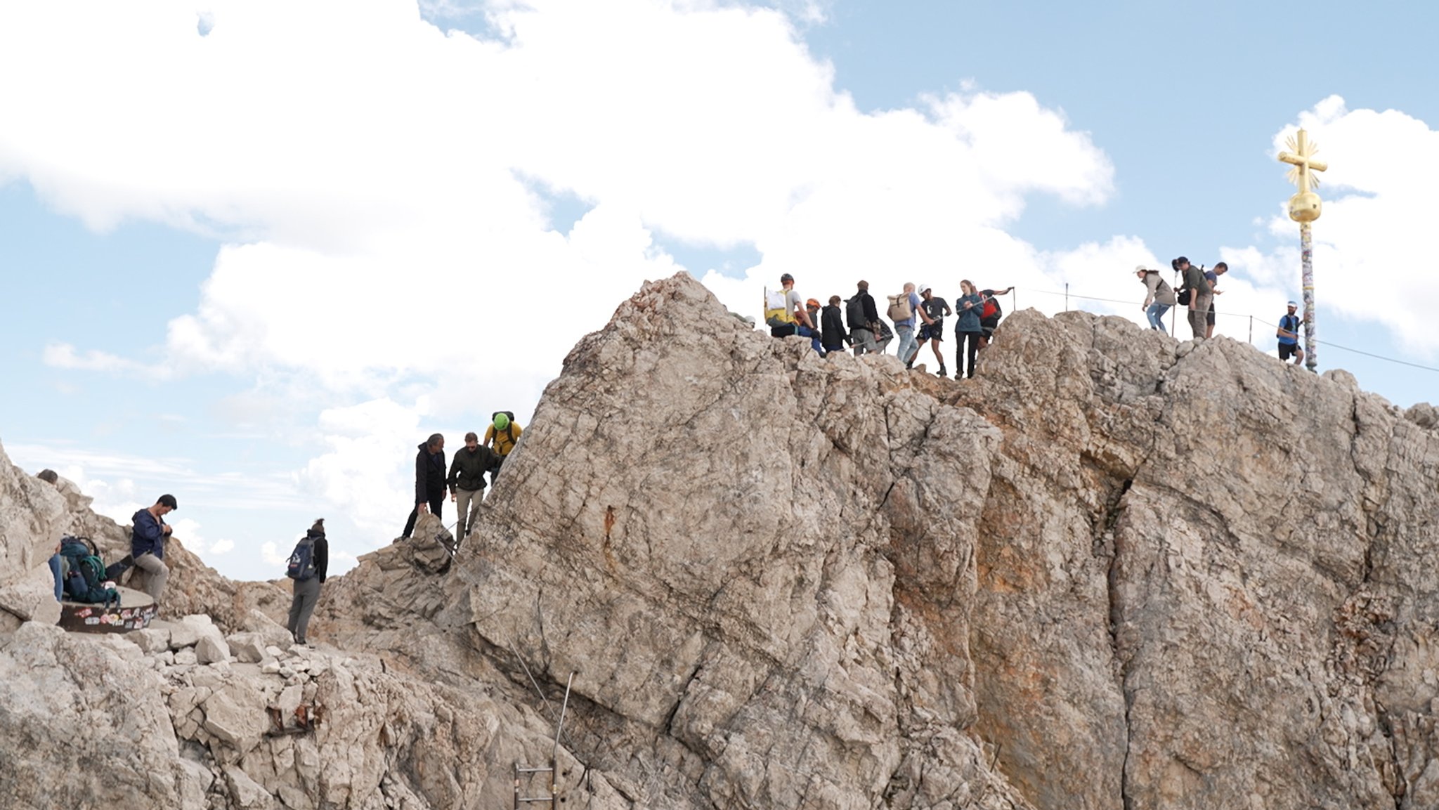 Viele Menschen drängen sich auf dem Klettersteig zum echten Gipfelkreuz.