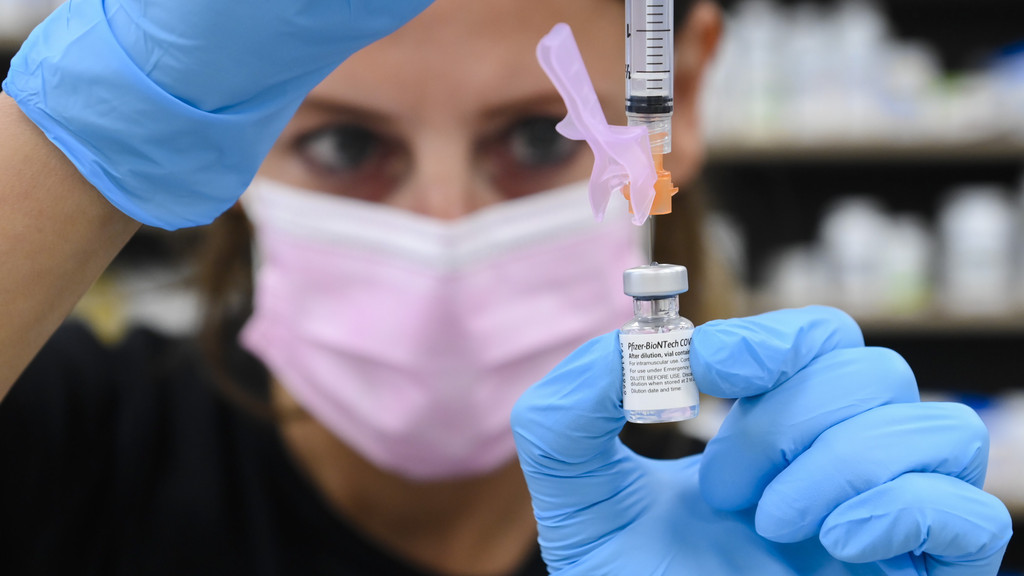 Frau zieht Spritze mit einer Dosis des Impfstoffs von Biontech/Pfizer auf