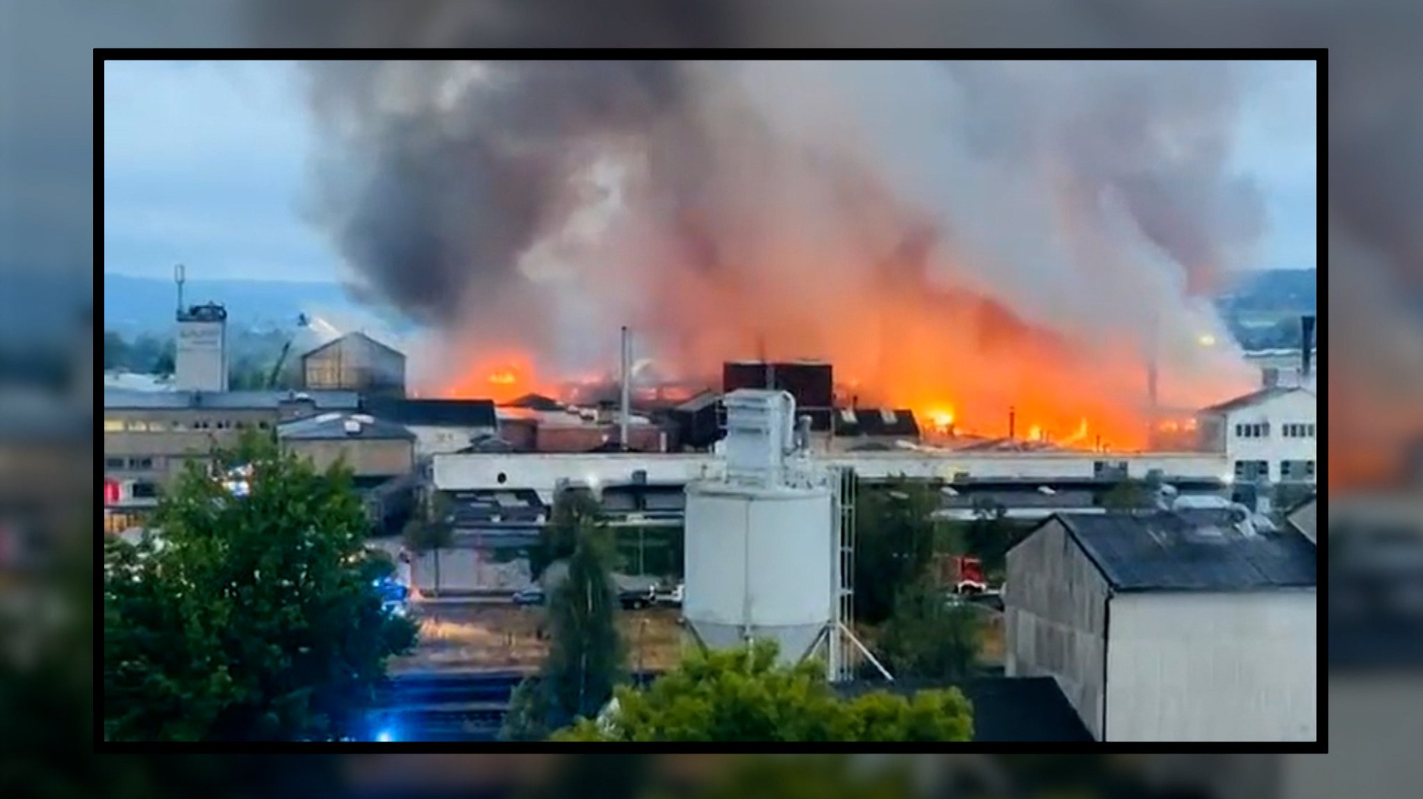 Ein Firmengebäude steht in Flammen. Dichter Rauch steigt empor. 