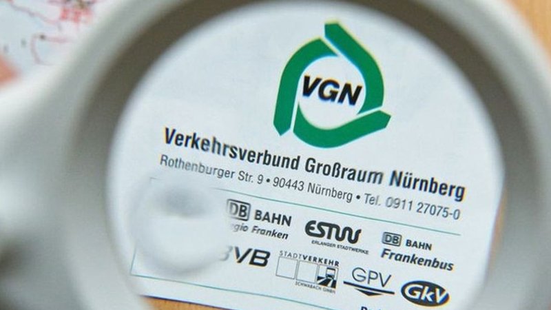 Das VGN-Symbol und die Adresse des Verkehrsverbund Großraum Nürnberg unter einer Lupe.