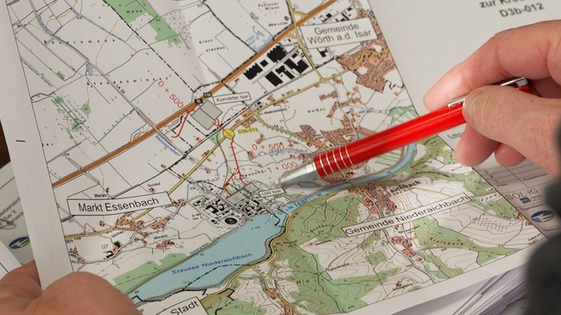 Eine Hand zeigt mit einem Stift etwas auf einer Landkarte. 