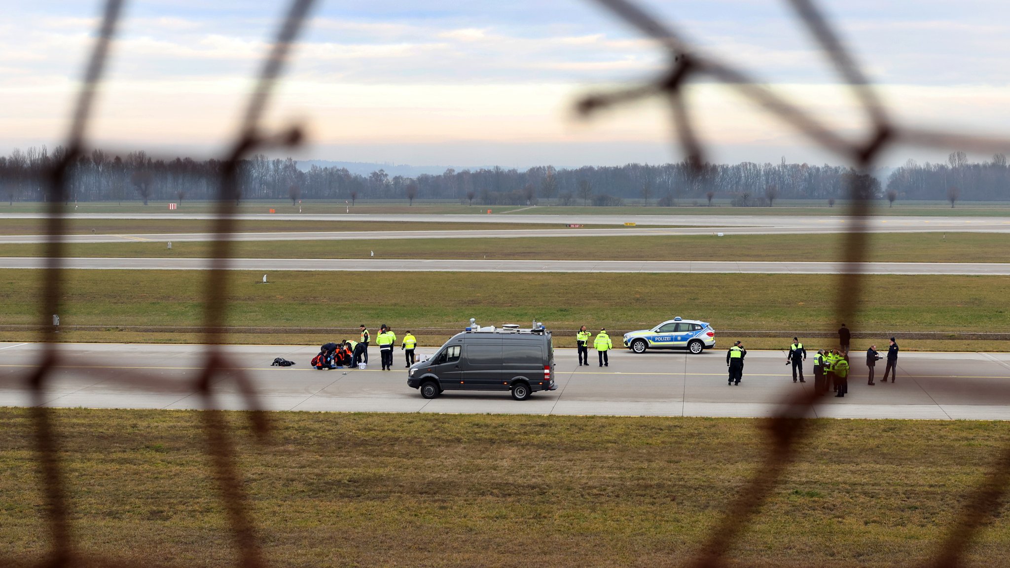 Vier Klimaaktivisten sitzen mit angeklebten Händen auf dem Zubringer einer Start-und Landebahn am Airport Franz-Josef-Strauß. (Archivbild: 08.12.2022)