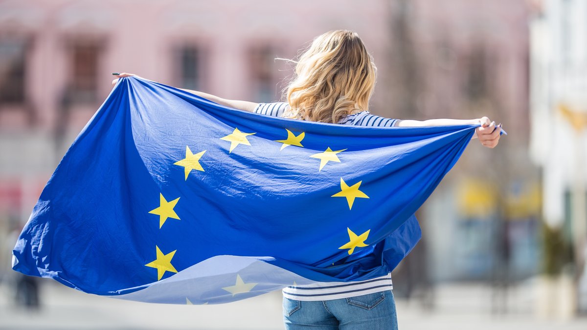 Eine junge Frau hält eine Europaflagge.