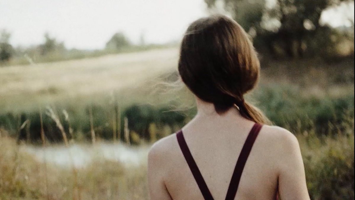 Ein junges Mädchen blickt Mitte der 80er Jahre an einem Fluß in der DDR auf die nahe West-Grenze in "In die Sonne schauen".