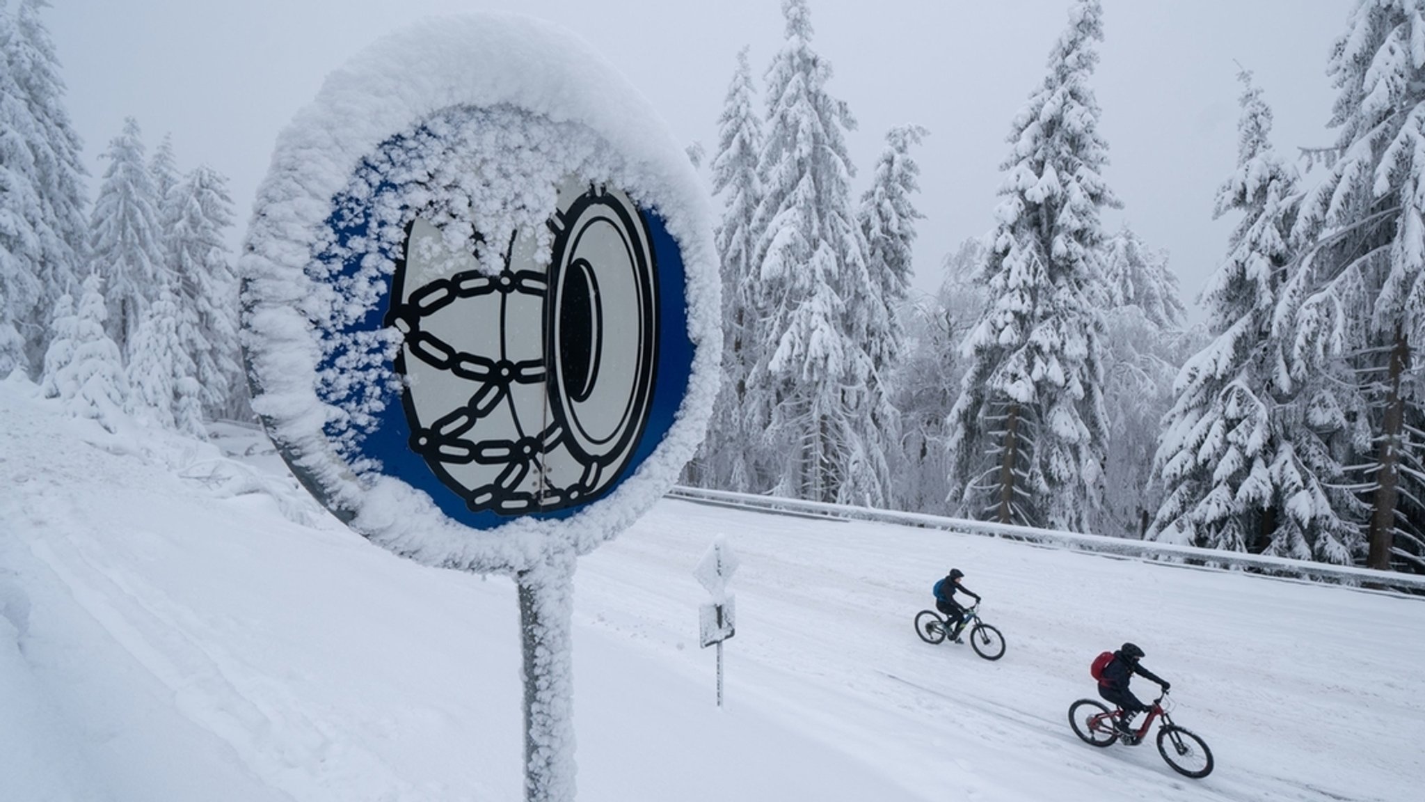 Blaues Schild mit weißem Reifensymbol mit Schneeketten