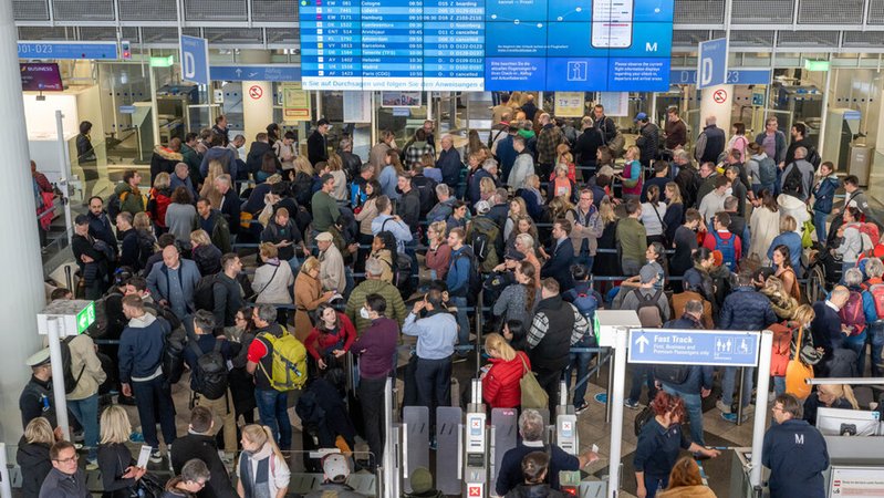 Passagiere am Münchner Flughafen stehen in der Abflughalle in Schlangen an | Bild: dpa-Bildfunk/Peter Kneffel Passagiere am Münchner Flughafen stehen in der Abflughalle in Schlangen an