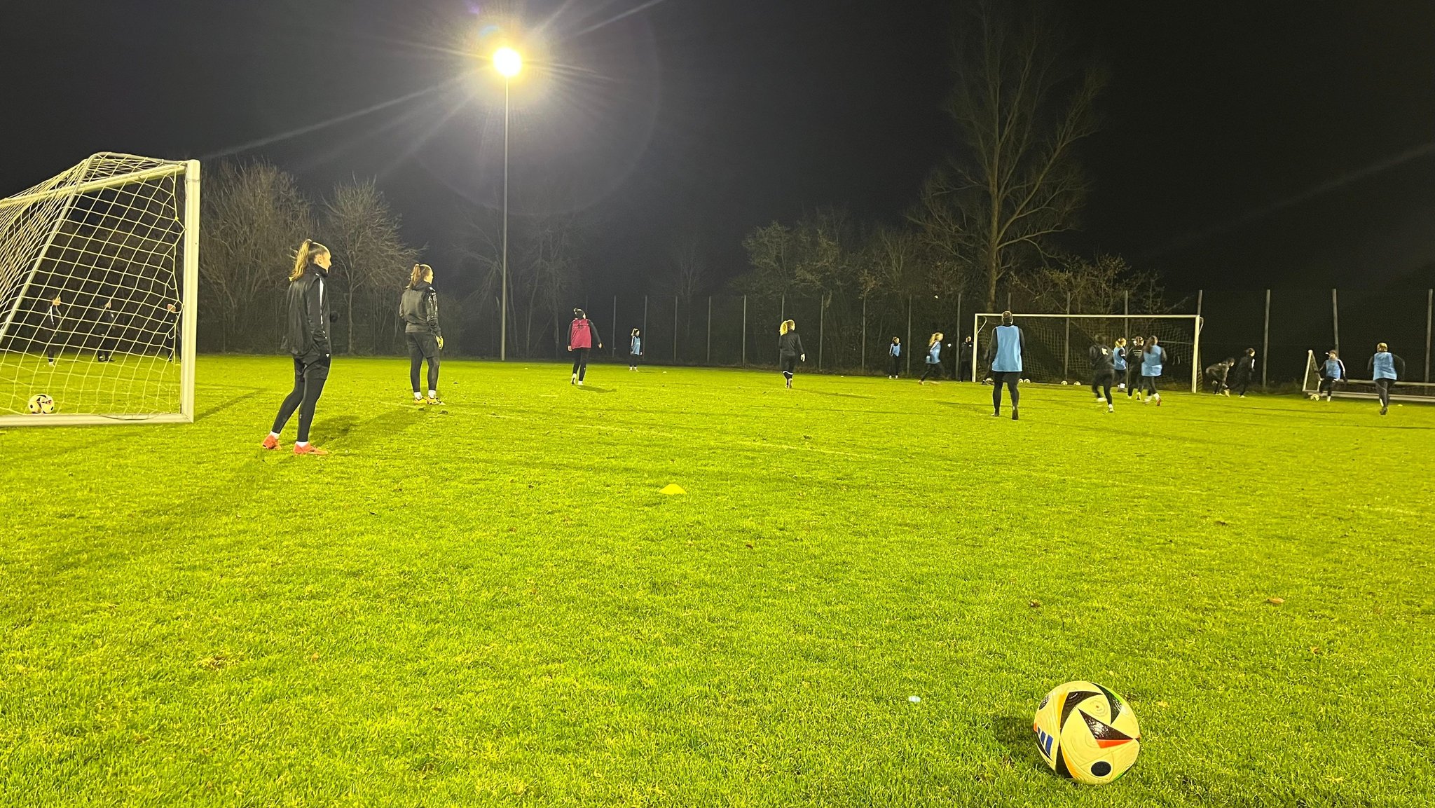 Fußballerinnen trainieren auf einem Sportplatz.