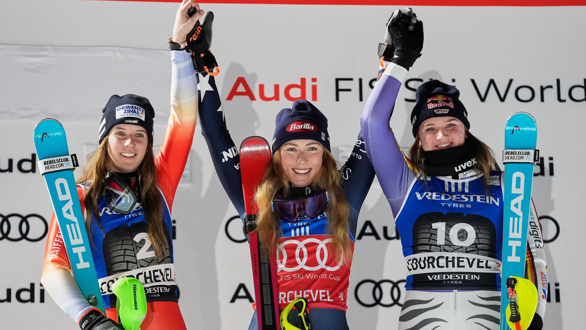 16.12.2025, Frankreich, Courchevel: Mikaela Shiffrin (M, USA) jubelt auf dem Podium neben der zweitplatzierten Camille Rast (l, Schweiz) und der drittplatzierten Emma Aicher (Deutschland) über ihren Sieg beim alpinen Skiweltcup-Slalom der Damen. Foto: Giovanni Auletta/AP/dpa +++ dpa-Bildfunk +++