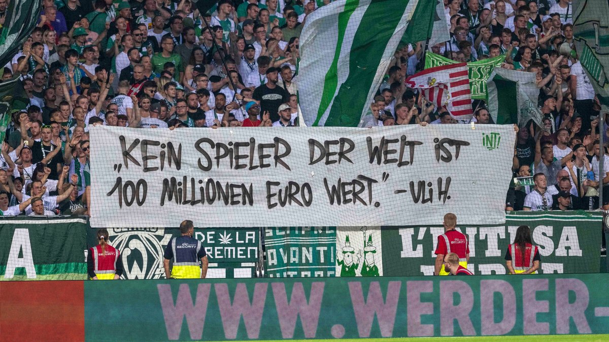 Bremer Fans zeigen ein Plakat mit der Aufschrift "Kein Spieler der Welt ist 100 Millionen Euro wert" - Uli Hoeneß. 