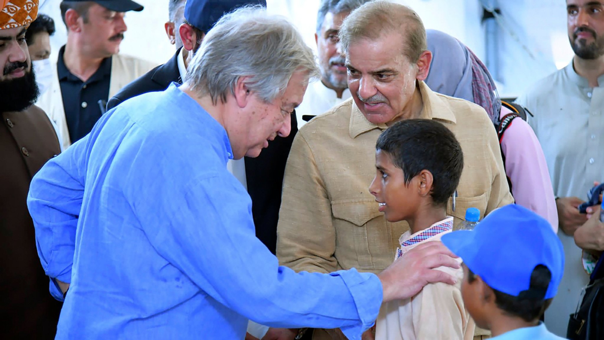 10.09.2022, Pakistan, Jaffarabad: Auf diesem vom Büro des pakistanischen Premierministers veröffentlichten Foto sprechen Premierminister Shahbaz Sharif (Mitte rechts) und UN-Generalsekretär Antonio Guterres (links) mit Kindern in einer Schule, die in einem Fluthilfe-Camp in Jaffarabad, Pakistan, eingerichtet wurde.