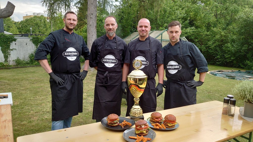 Die vier Kitchendudes aus Nürnberg und Fürth stehen hinter einem Tisch mit ihrem Pokal und mehreren Burgern.