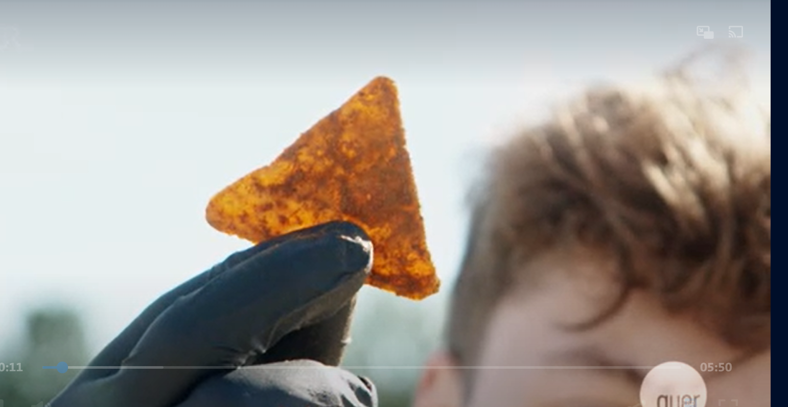 Ein Jugendlicher hält einen Tortilla-Chip mit Handschuh in die Luft
