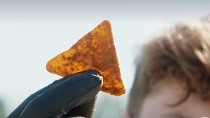 Ein Jugendlicher hält einen Tortilla-Chip mit Handschuh in die Luft