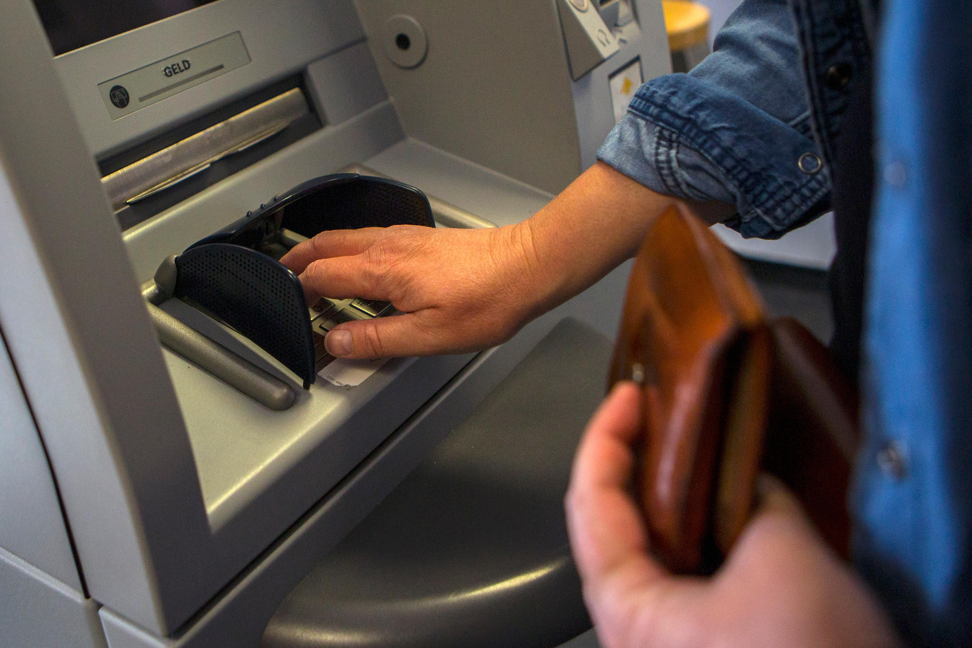Eine Frau gibt ihre PIN-Nummer beim Geldabheben an einem Geldautomaten ein.