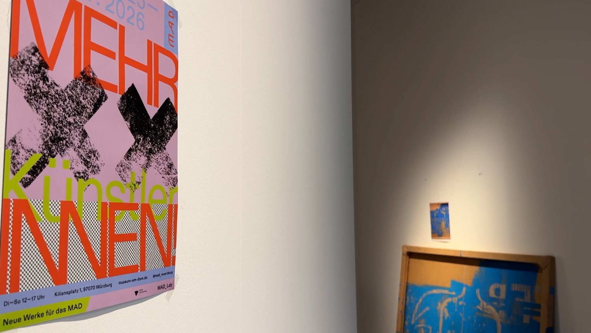 Ein Plakat, das für die Ausstellung "Mehr KünstlerINNEN" im Museum am Dom in Würzburg wirbt, hängt an einer Wand.