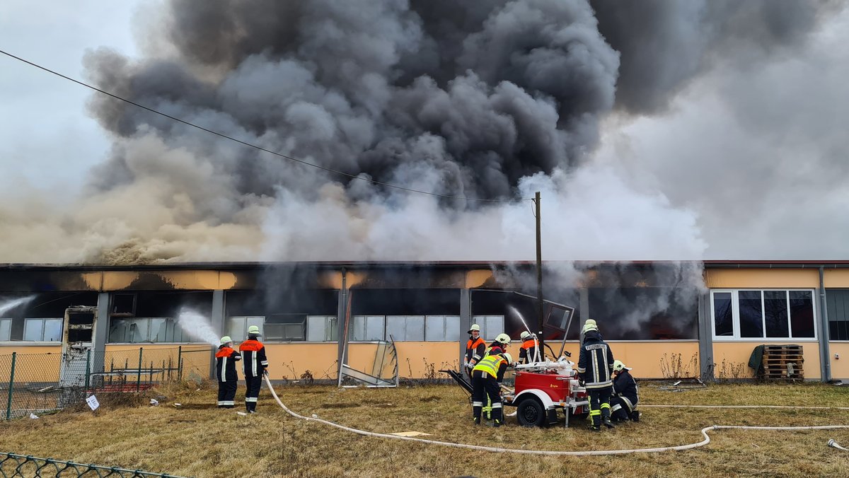 Feuerwehrleute löschen den Brand der Lagerhalle.