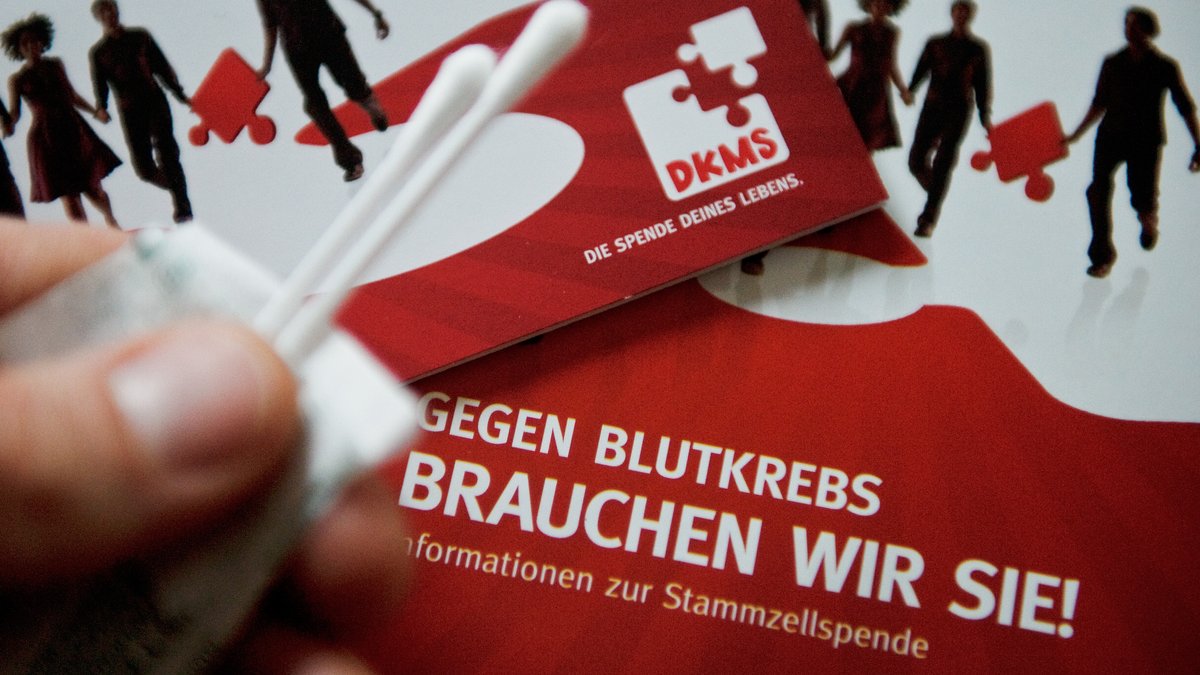 Infomaterial und Wattestäbchen für die Aufnahme in die Deutsche Knochenmarkspenderdatei (DKMS) auf einem Tisch. 