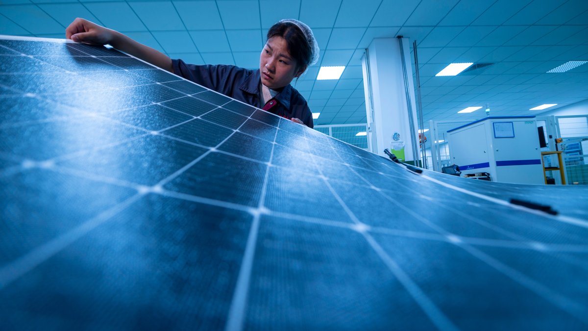 Chinesische Arbeiterin mit Solar-Paneelen