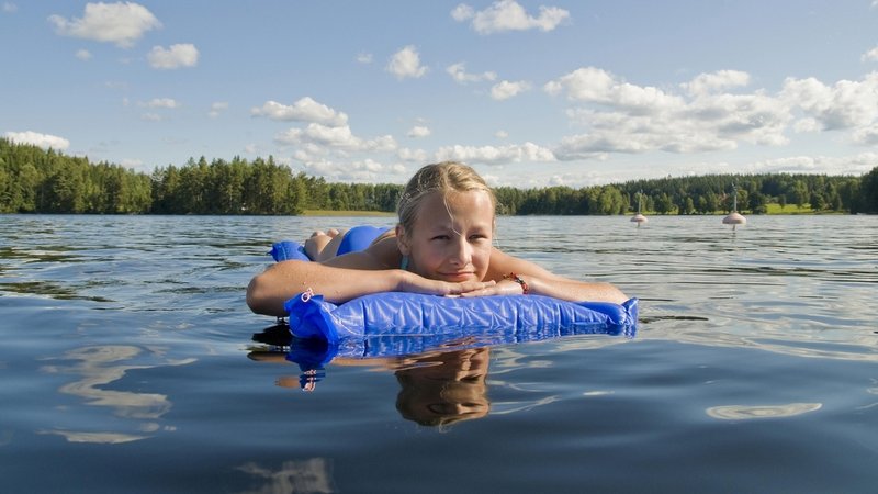 Mädchen treibt mit Lufmatratze auf einem See.