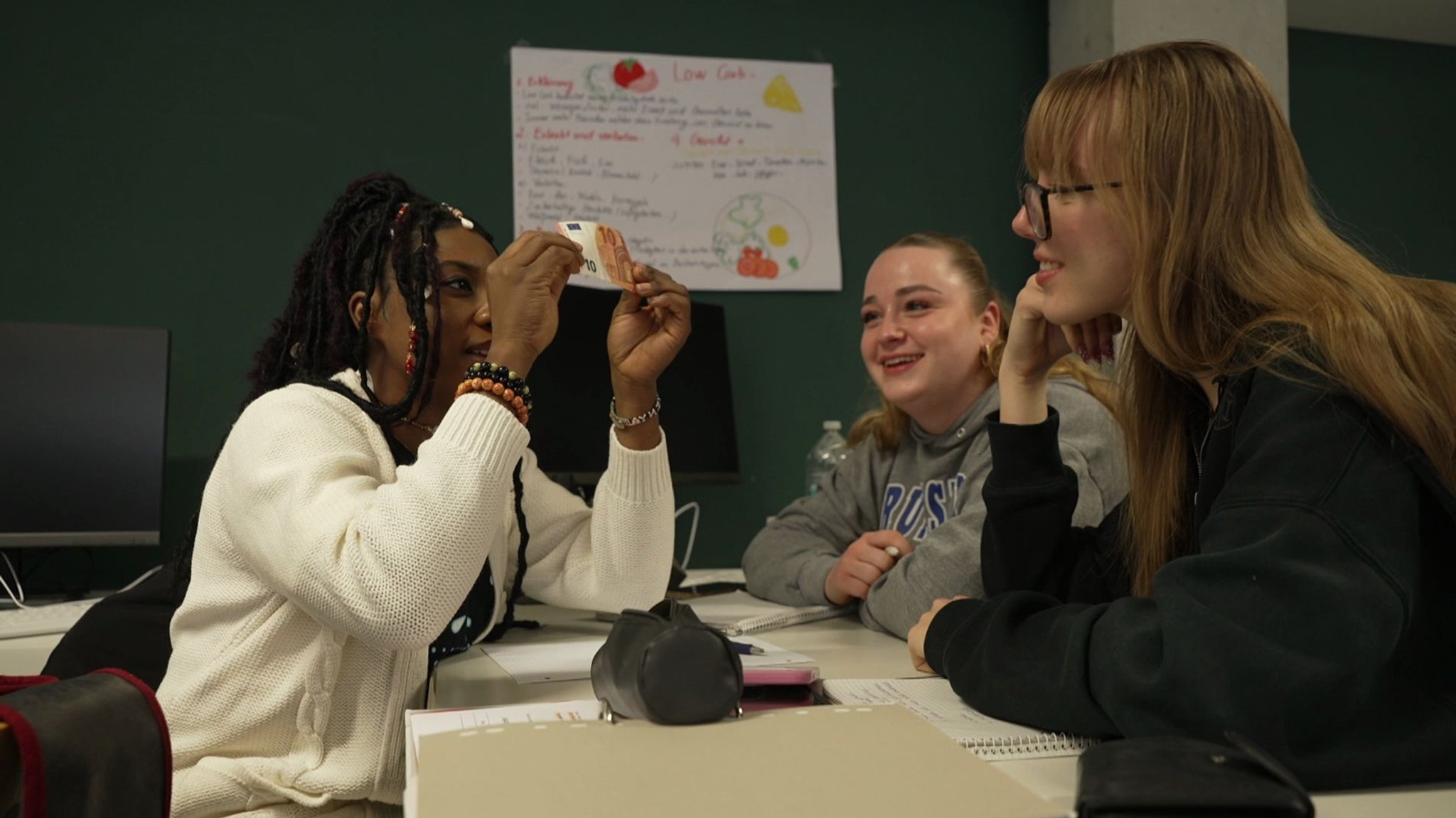 Hotelfach-Azubi Laeticia Sawadogo hält einen Zehn-Euro-Schein in die Höhe. | Bild: BR Hotelfach-Azubi Laeticia Sawadogo hält einen Zehn-Euro-Schein in die Höhe.