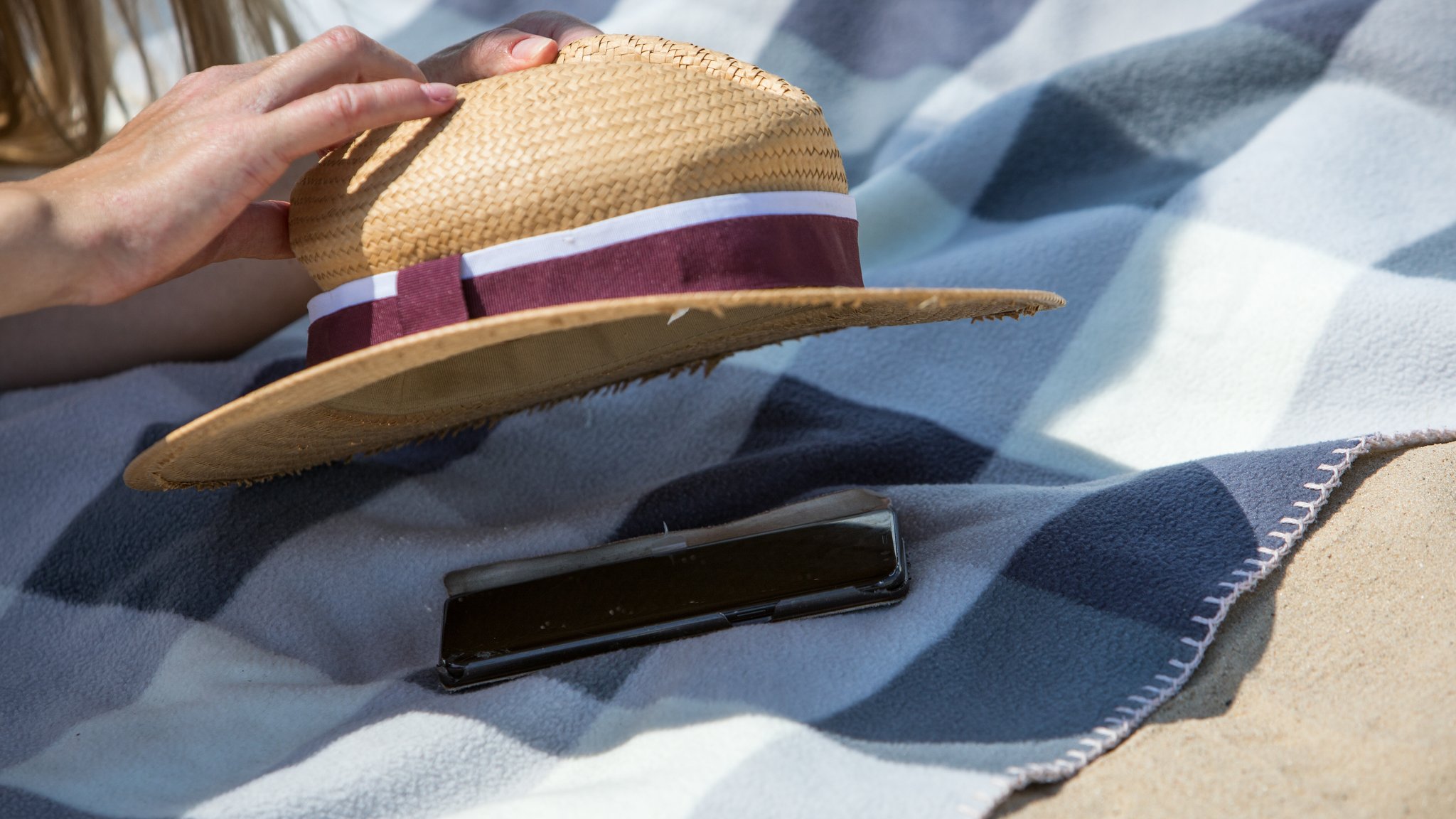 Frau deckt Smartphone mit einem Hut zu