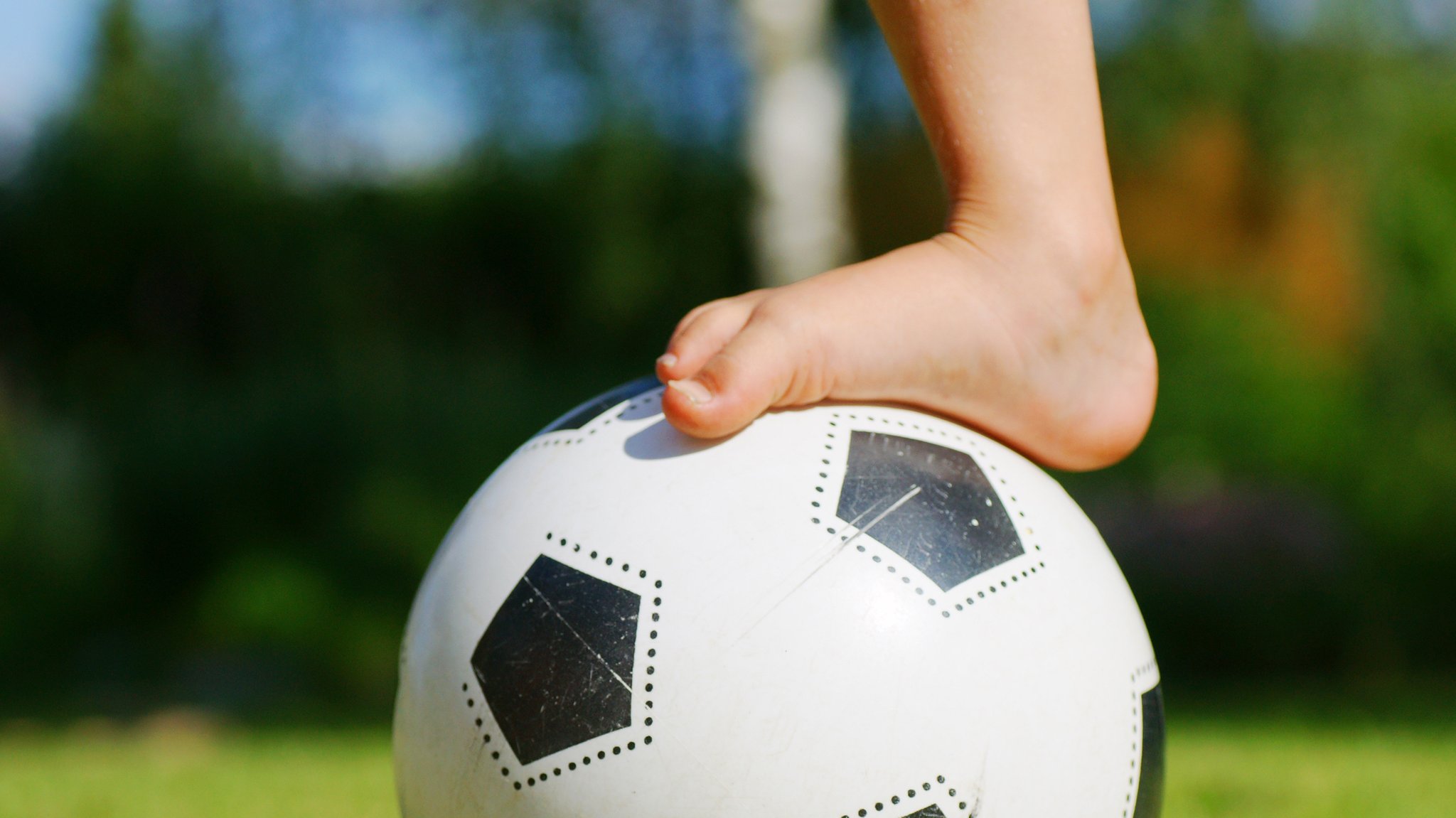 Nackter Kinderfuß auf einem Fussball