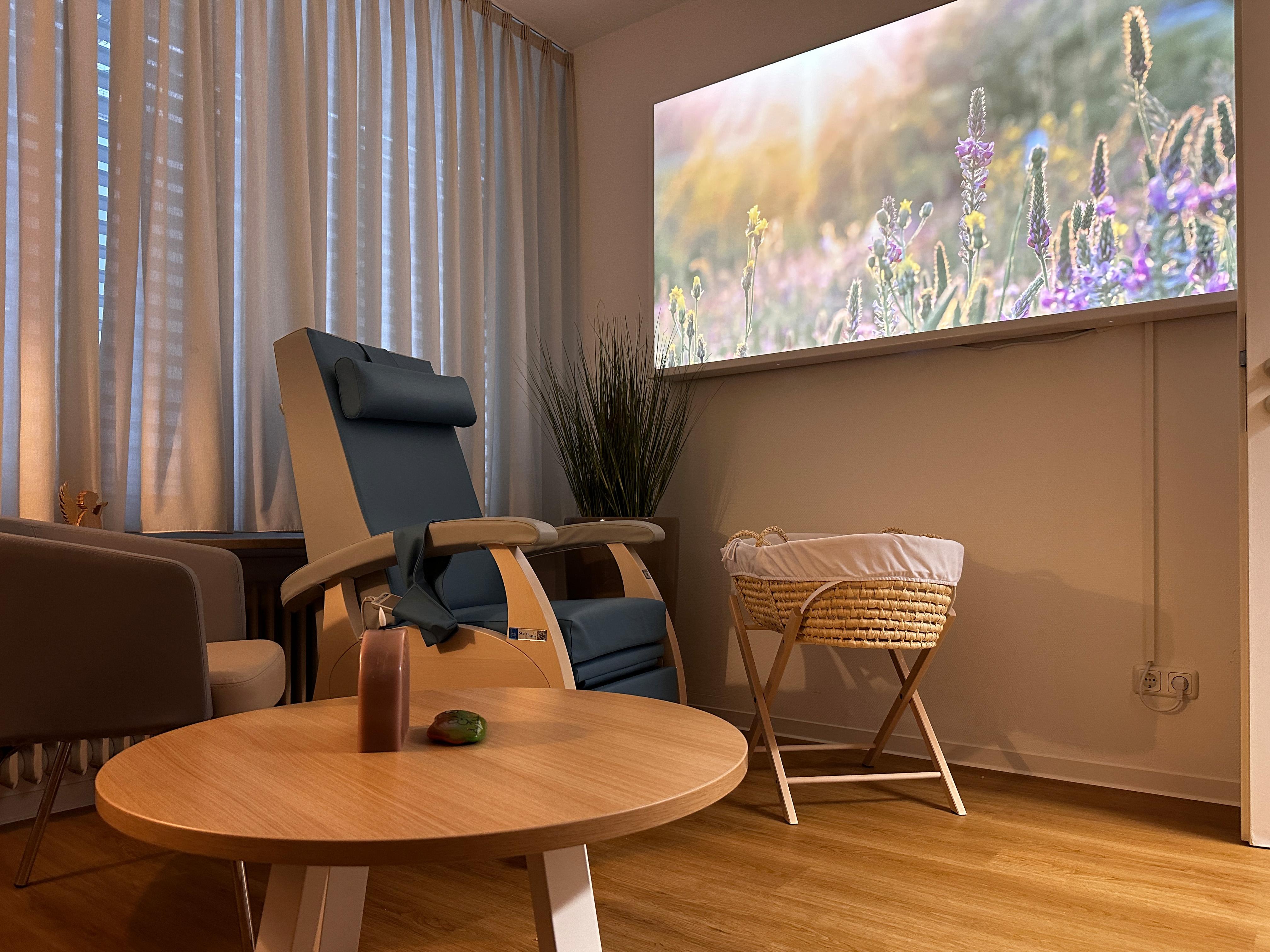 Raum mit Babybett und Sessel.