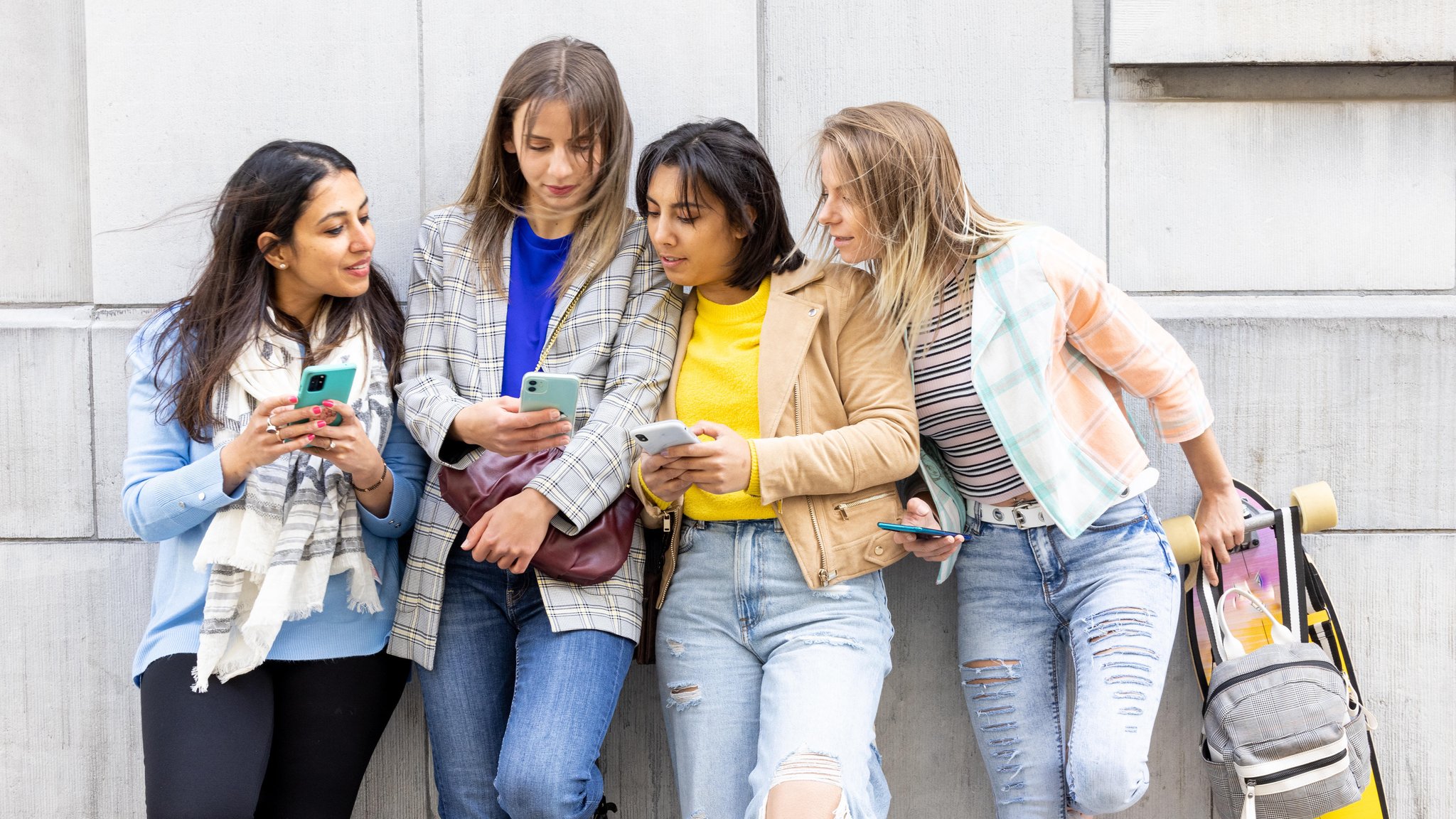 Eine Gruppe von Teenagern schaut gemeinsam in ihre Smartphones